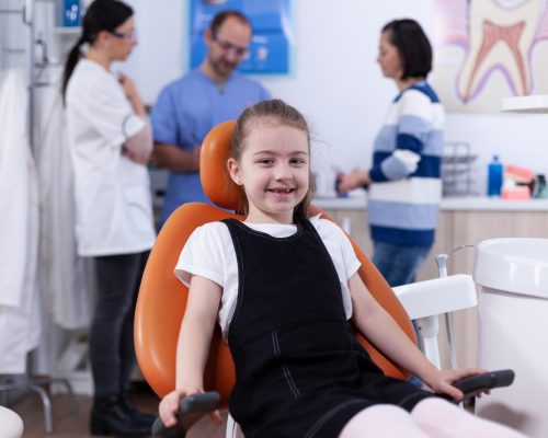 cheerful-kid-sitting-chair-dentist-office-during-visit-bad-tooth-treatment-parent-disscusing-with-doctor-child-with-her-mother-during-teeth-check-up-with-stomatolog-sitting-chair